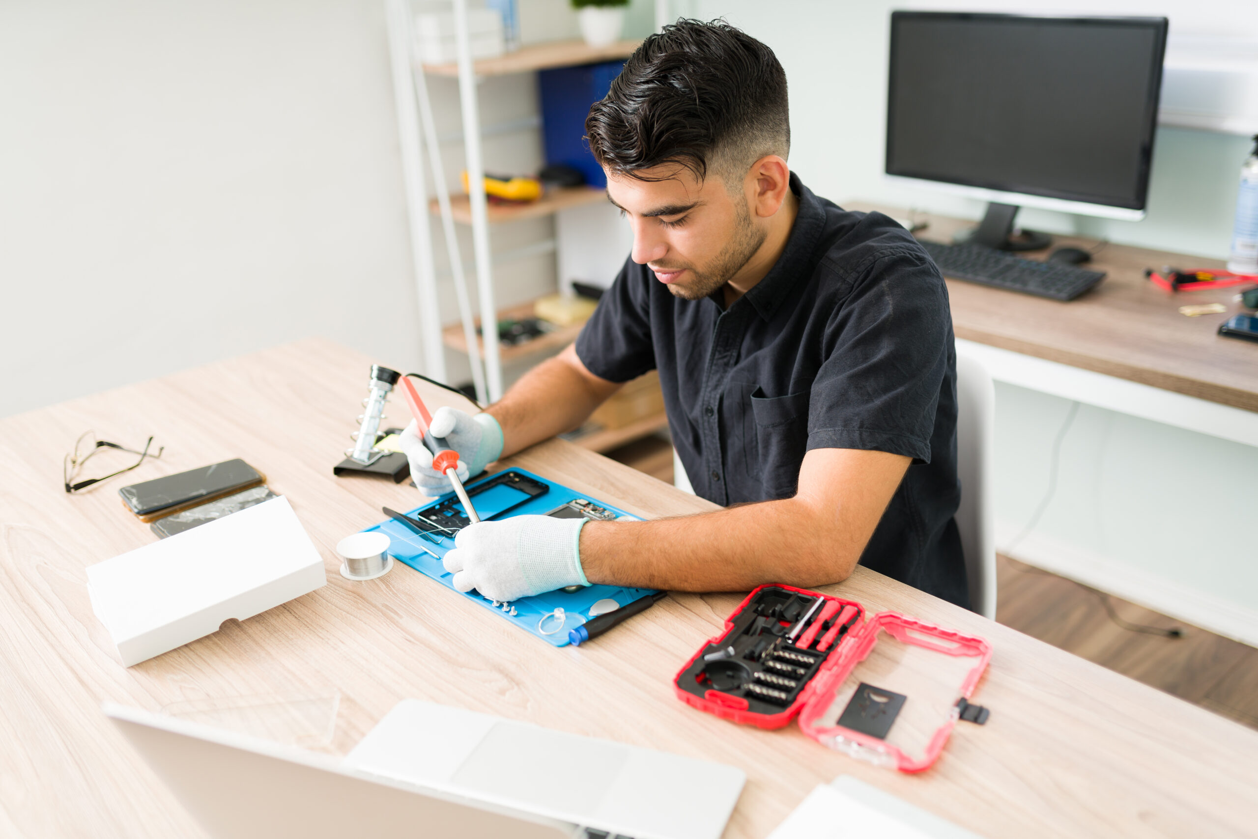 Latin technician soldering a smartphone component